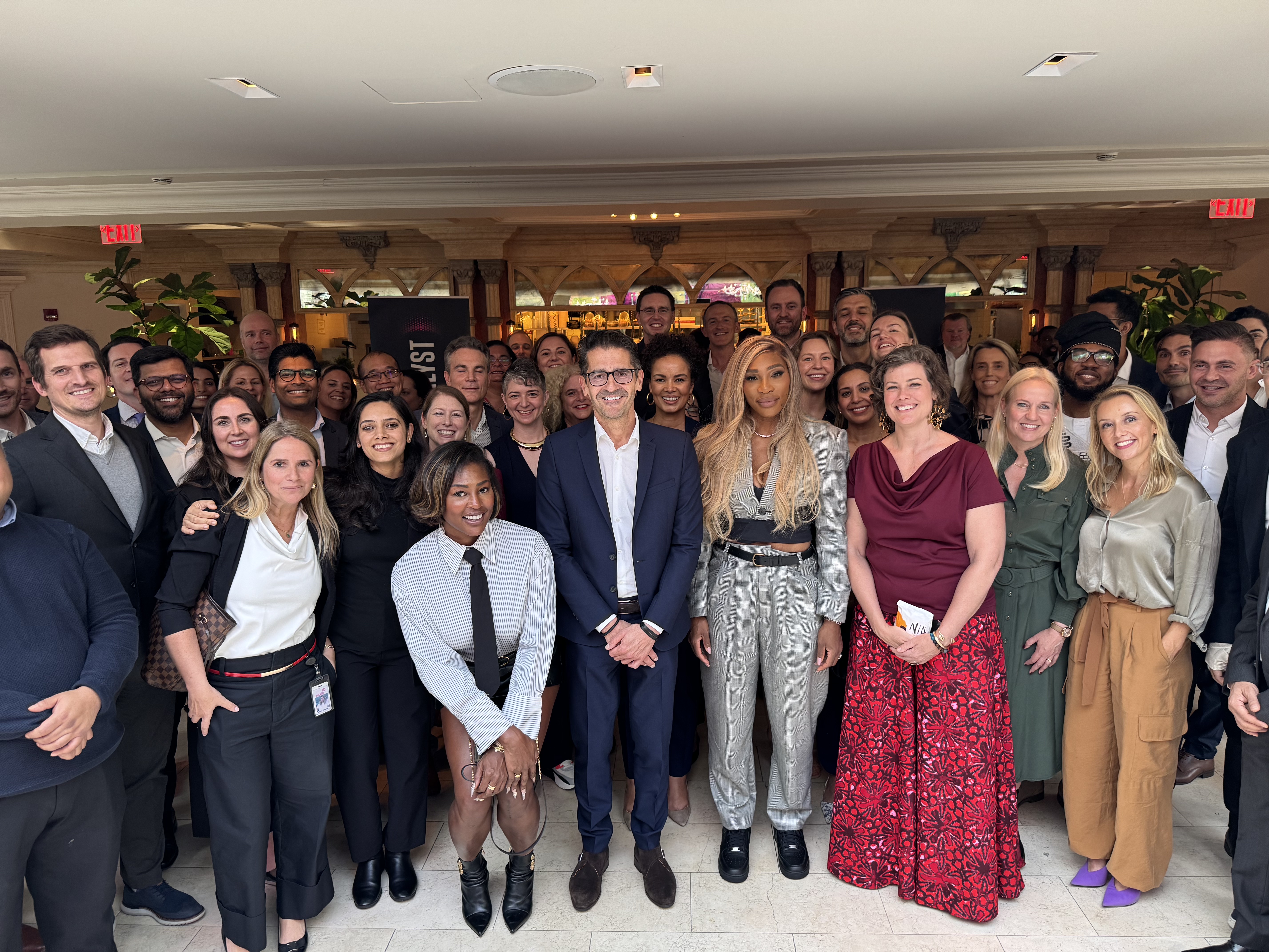 A large group of people is gathered indoors, posing for a group photo