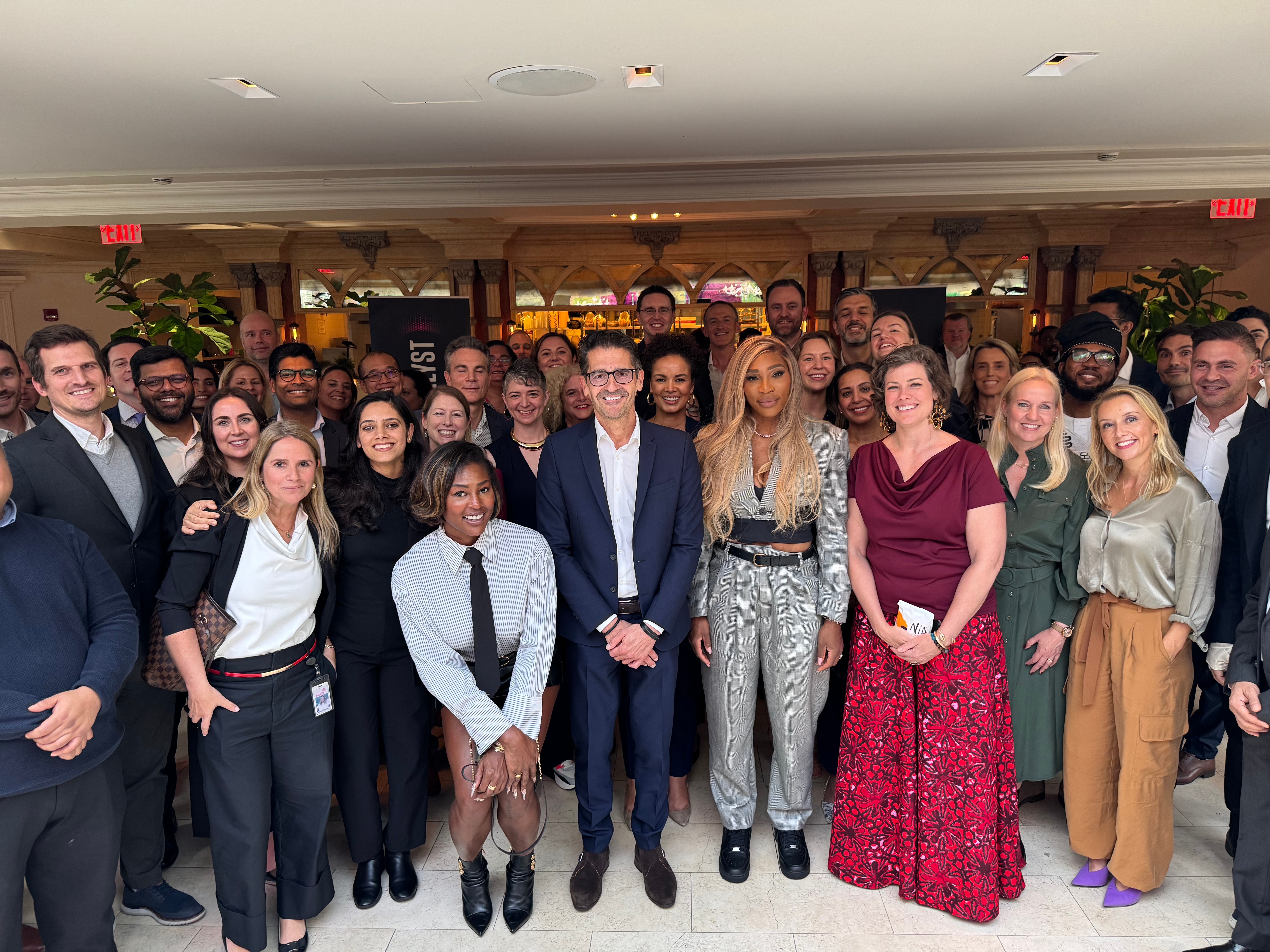 A large group of people is gathered indoors, posing for a group photo