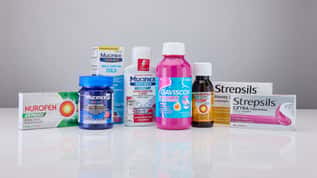 Selection of over-the-counter cold, flu, pain relief, and digestive health products displayed on a white surface