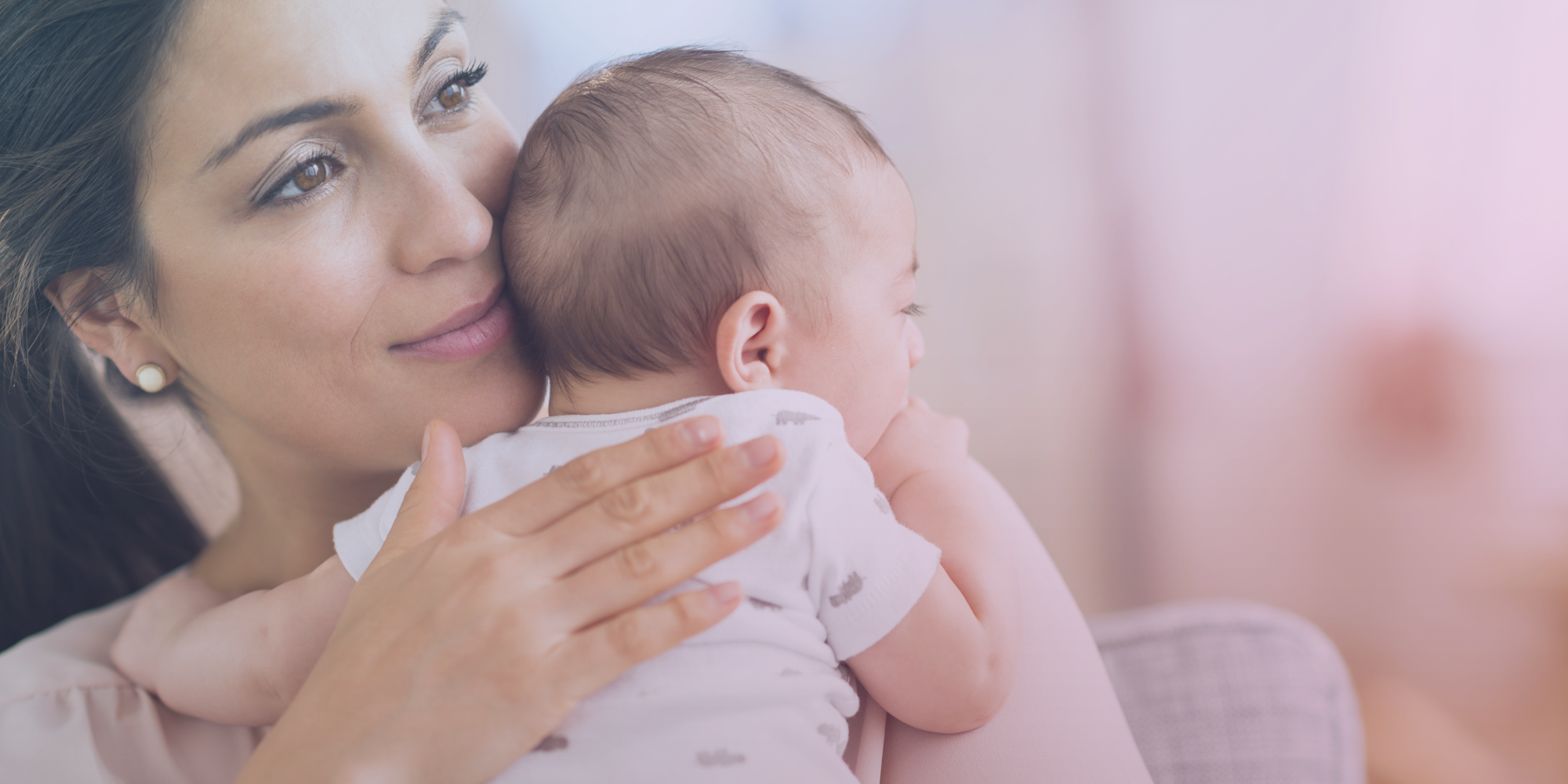 Mother holding a baby close indoors with soft natural lighting