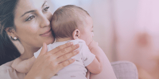 Mother holding a baby close indoors with soft natural lighting