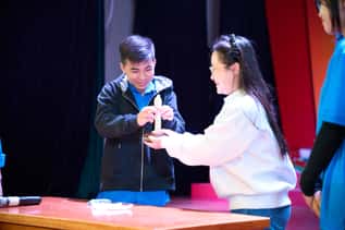 Two people on stage smiling while holding a small object together