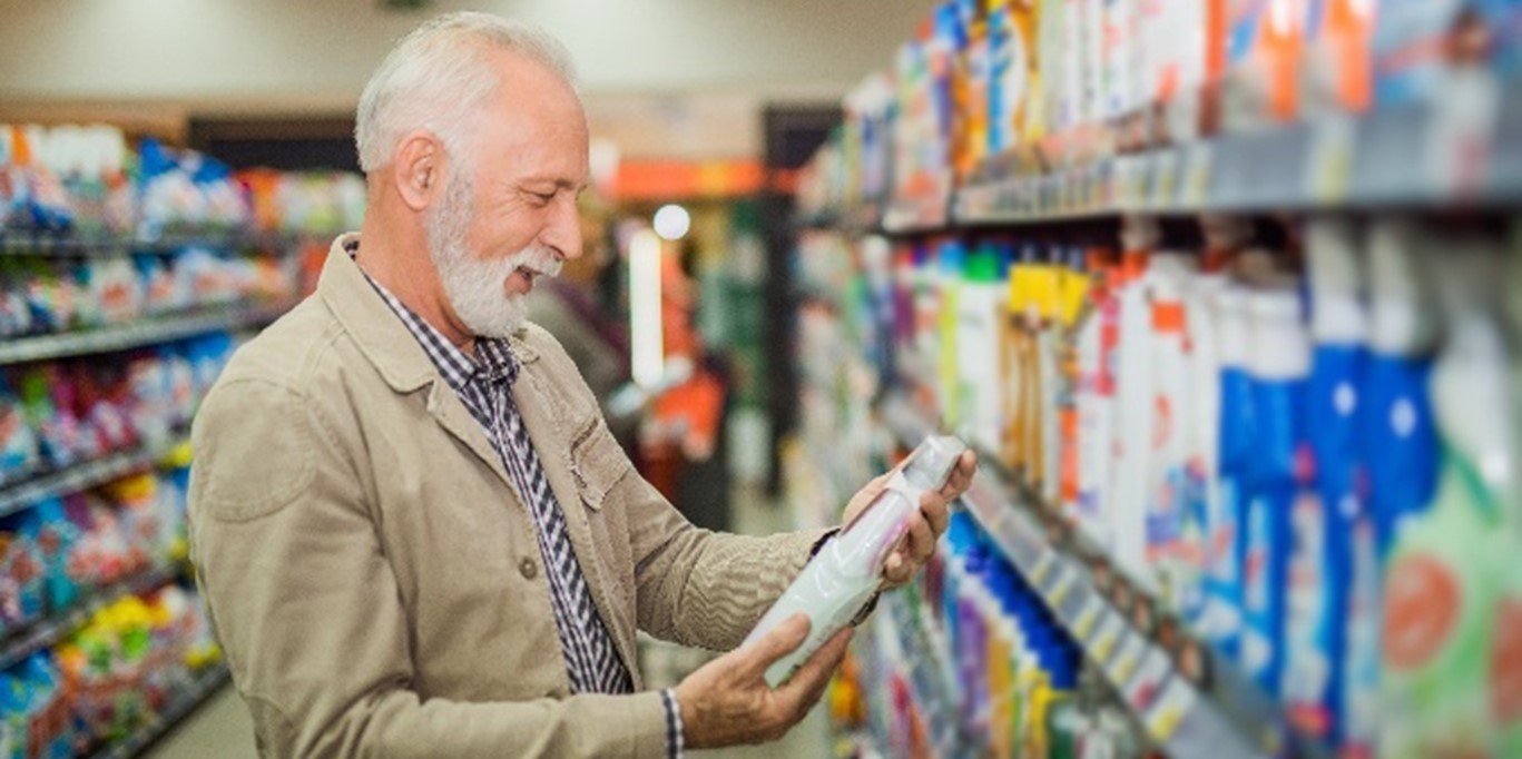 Older adult shopping for household products in a grocery store aisle