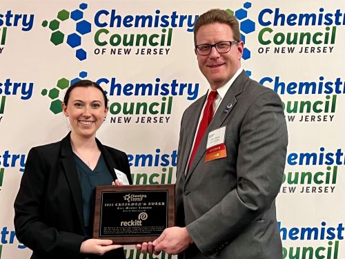 Two professionals presenting an award on behalf of Reckitt at a Chemistry Council of New Jersey recognition event in front of a branded backdrop