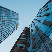 Upward view of modern glass skyscrapers converging against a clear sky.