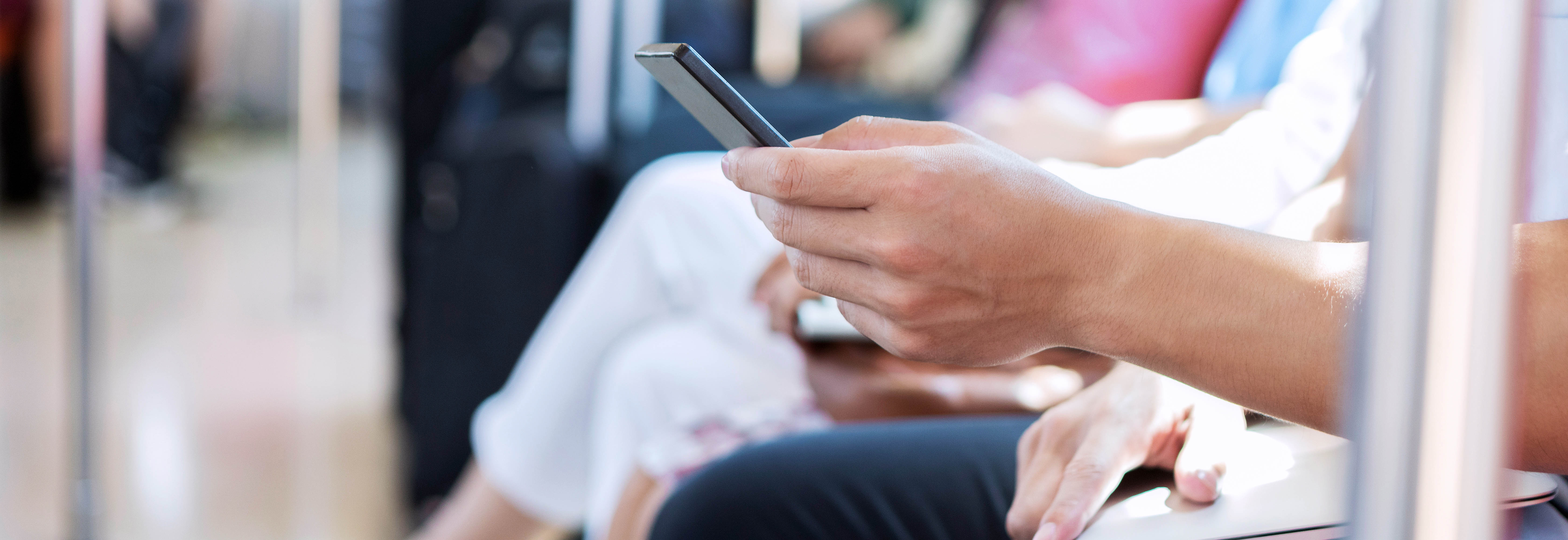 Close-up of people using smartphones while seated in a public waiting area