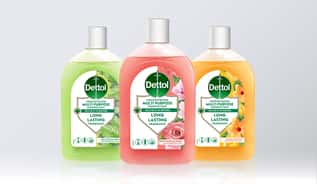 Three Dettol disinfectant bottles in green, pink, and orange.