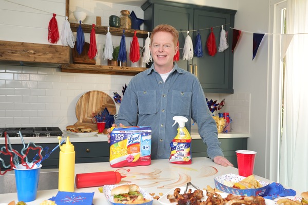 Person standing at a table with food and cleaning products during a festive gathering