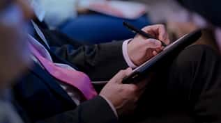 Person in a suit taking notes on a tablet