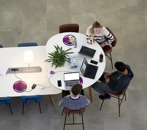 Overhead view of people working together at a table with laptops