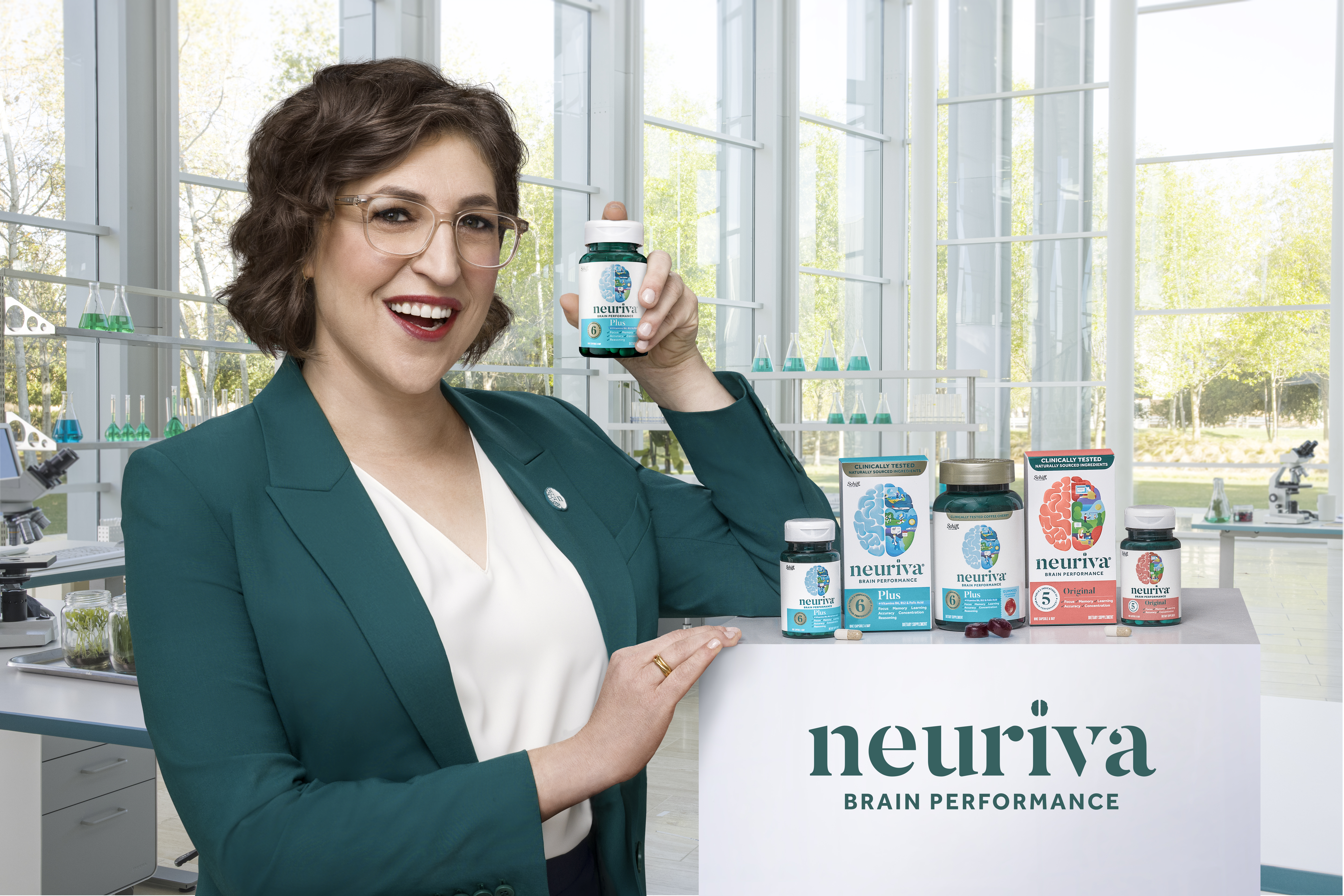 Woman holding a Neuriva supplement bottle beside Neuriva Brain Performance products in a laboratory setting