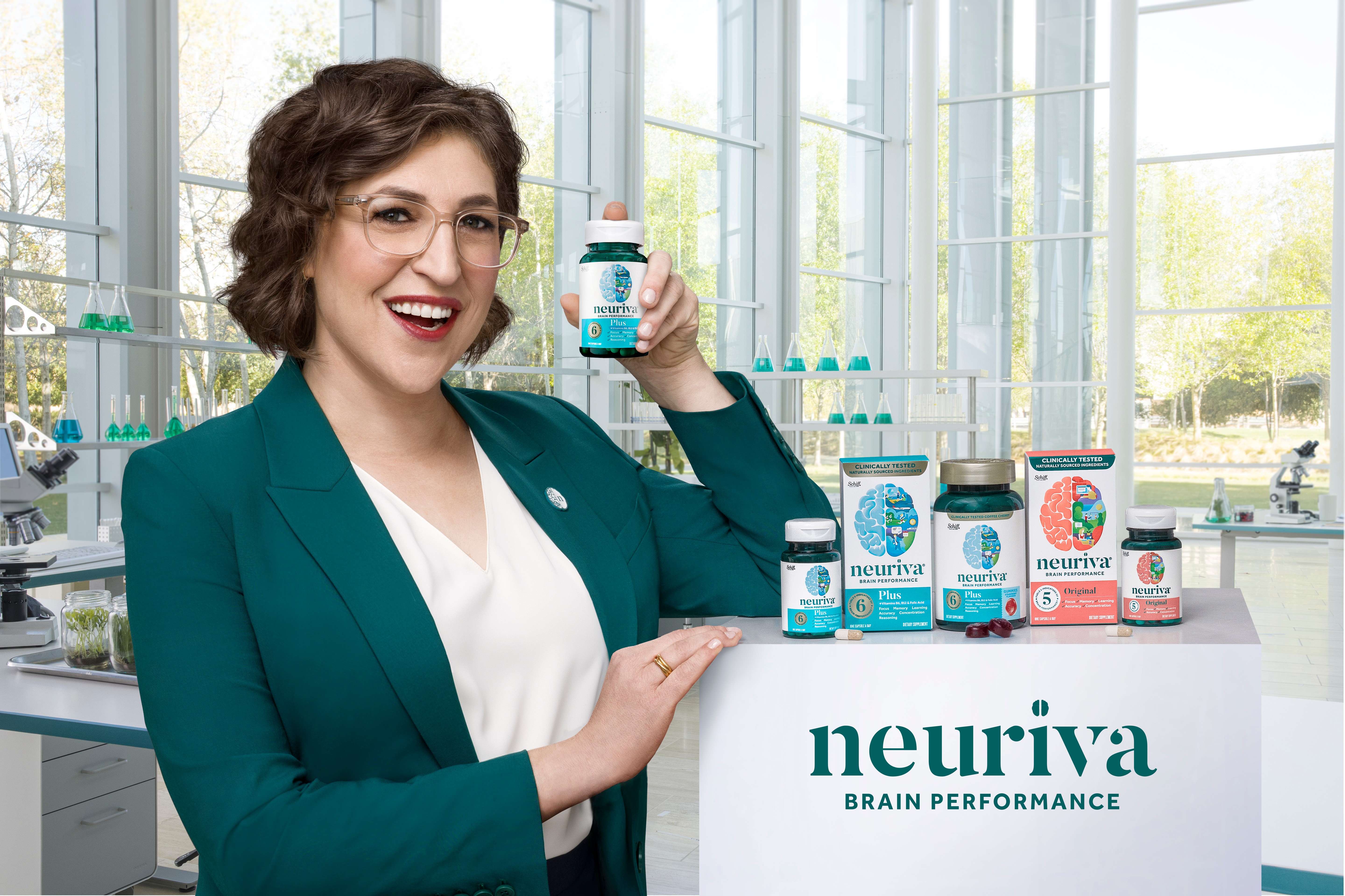 Woman holding a Neuriva supplement bottle beside Neuriva Brain Performance products in a laboratory setting
