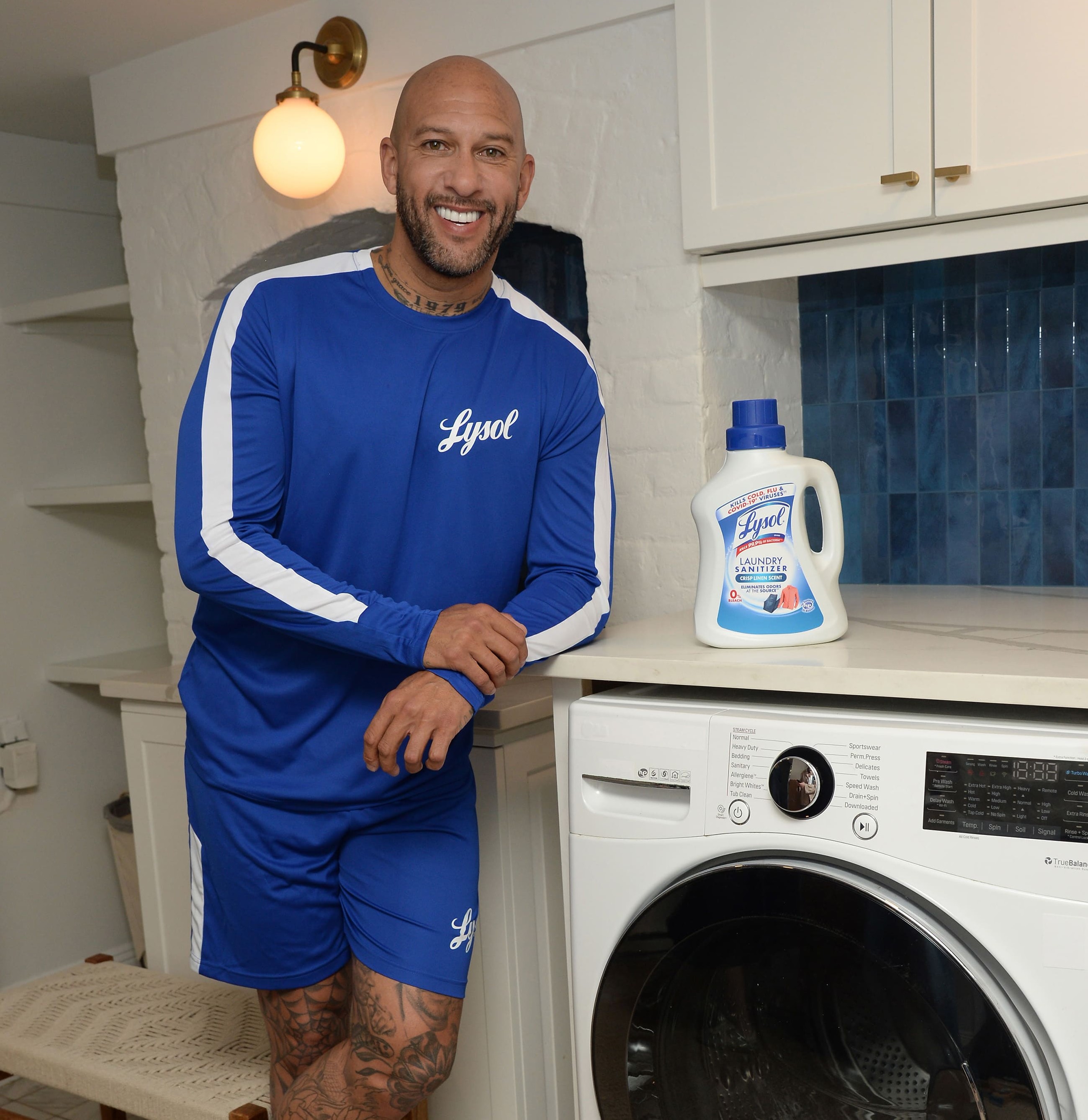 Person standing next to a washing machine and laundry sanitizer in a laundry room