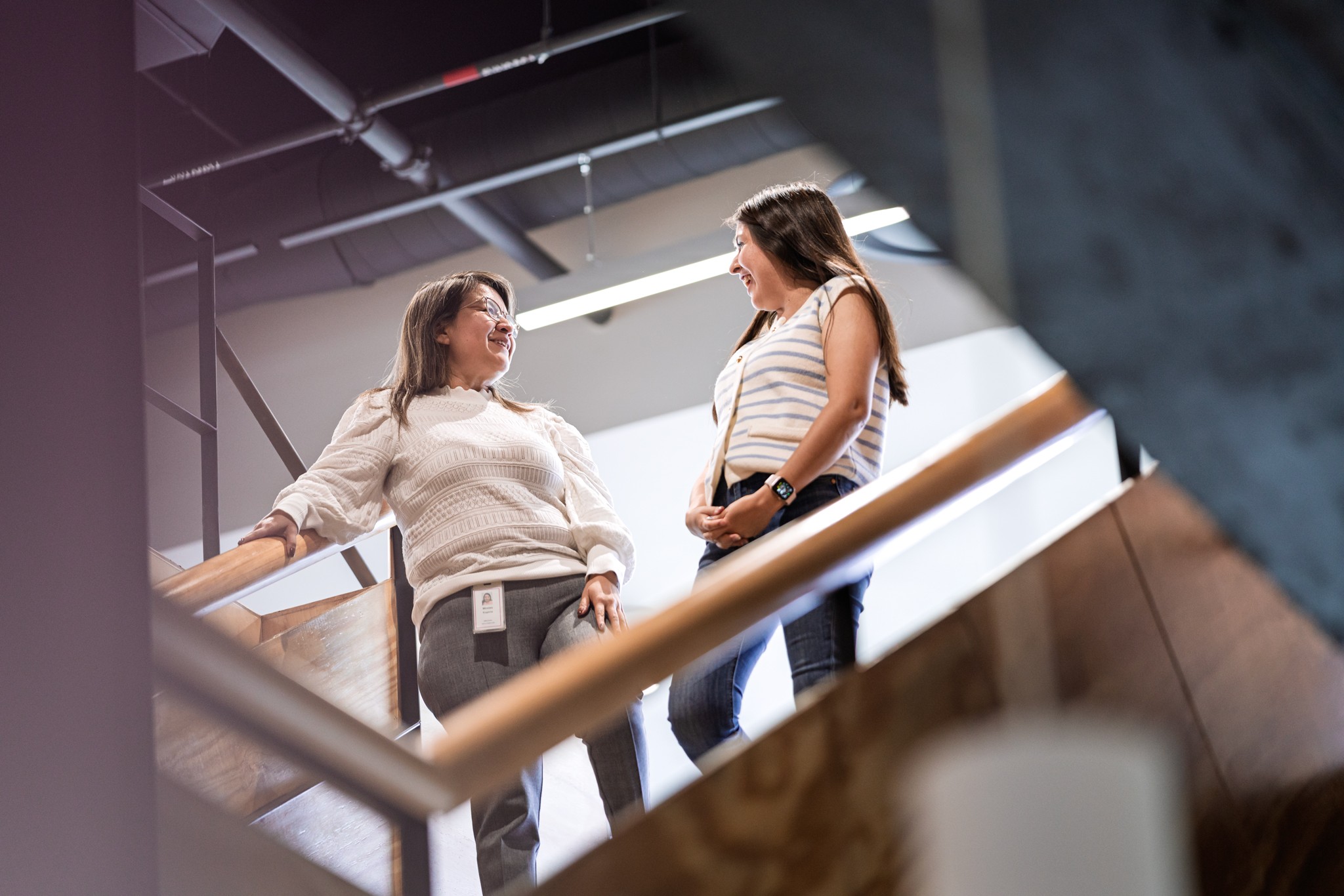 Two colleagues talking on a staircase in a modern office