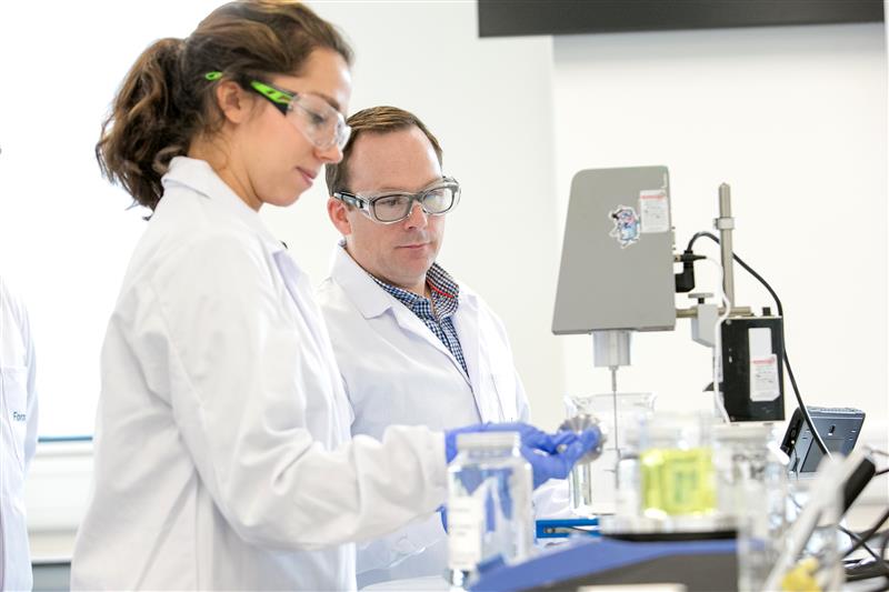 Two scientists in safety gear working in a lab