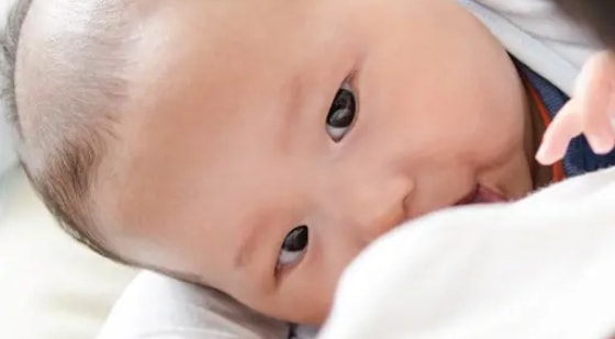 Close-up of a baby lying down and looking forward.