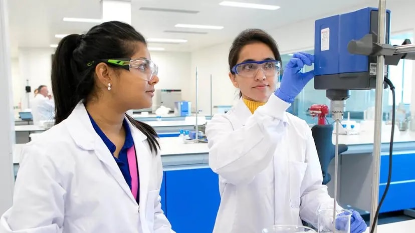 Two scientists in safety glasses operating lab equipment in a laboratory.