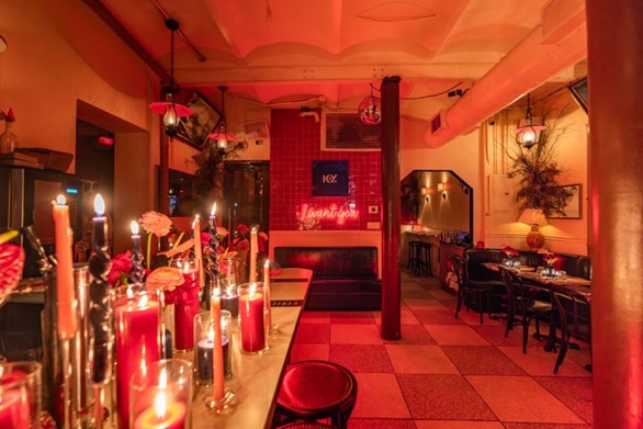 Warmly lit restaurant interior with candlelit tables, red ambient lighting, and dining seating