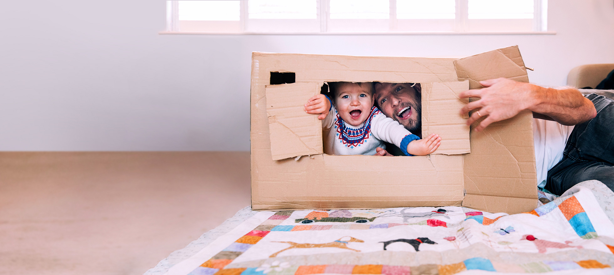 Father and child playing inside a cardboard box at home