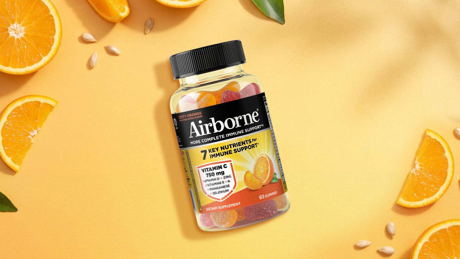 A bottle of Airborne immune support gummies in zesty orange flavor against an orange background with orange slices and seeds in the top left and bottom right corners.