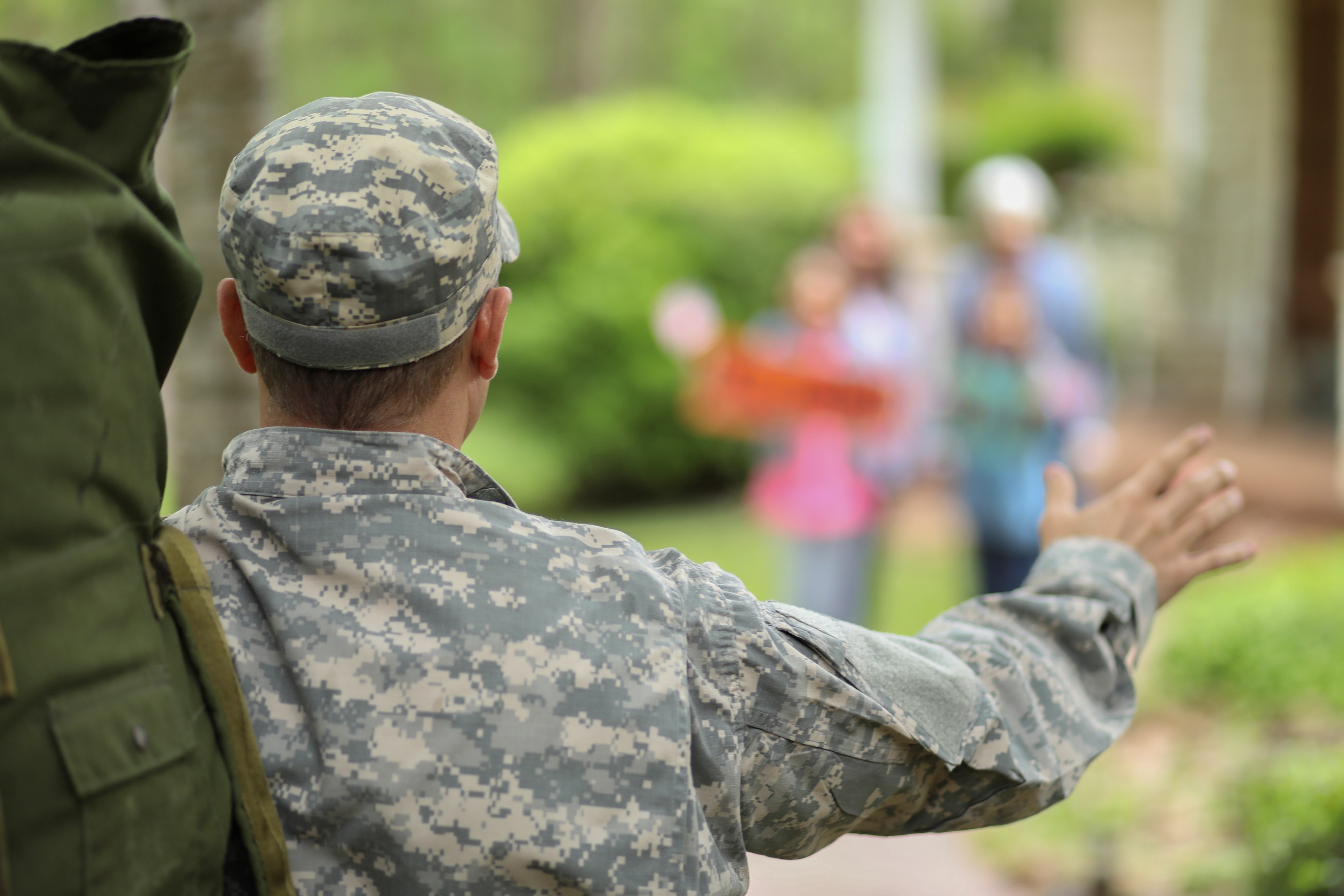Service member in military uniform waving to family members in the distance