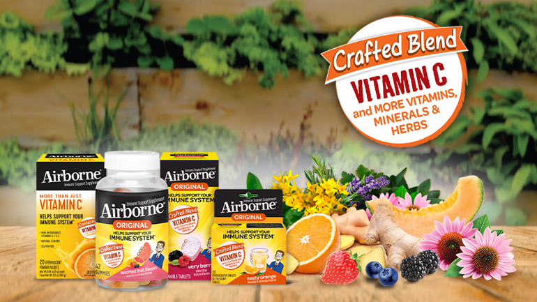 A variety of Airborne Original immune support supplements displayed with fresh fruits, flowers, and herbs on a wooden surface with a blurred garden background.
