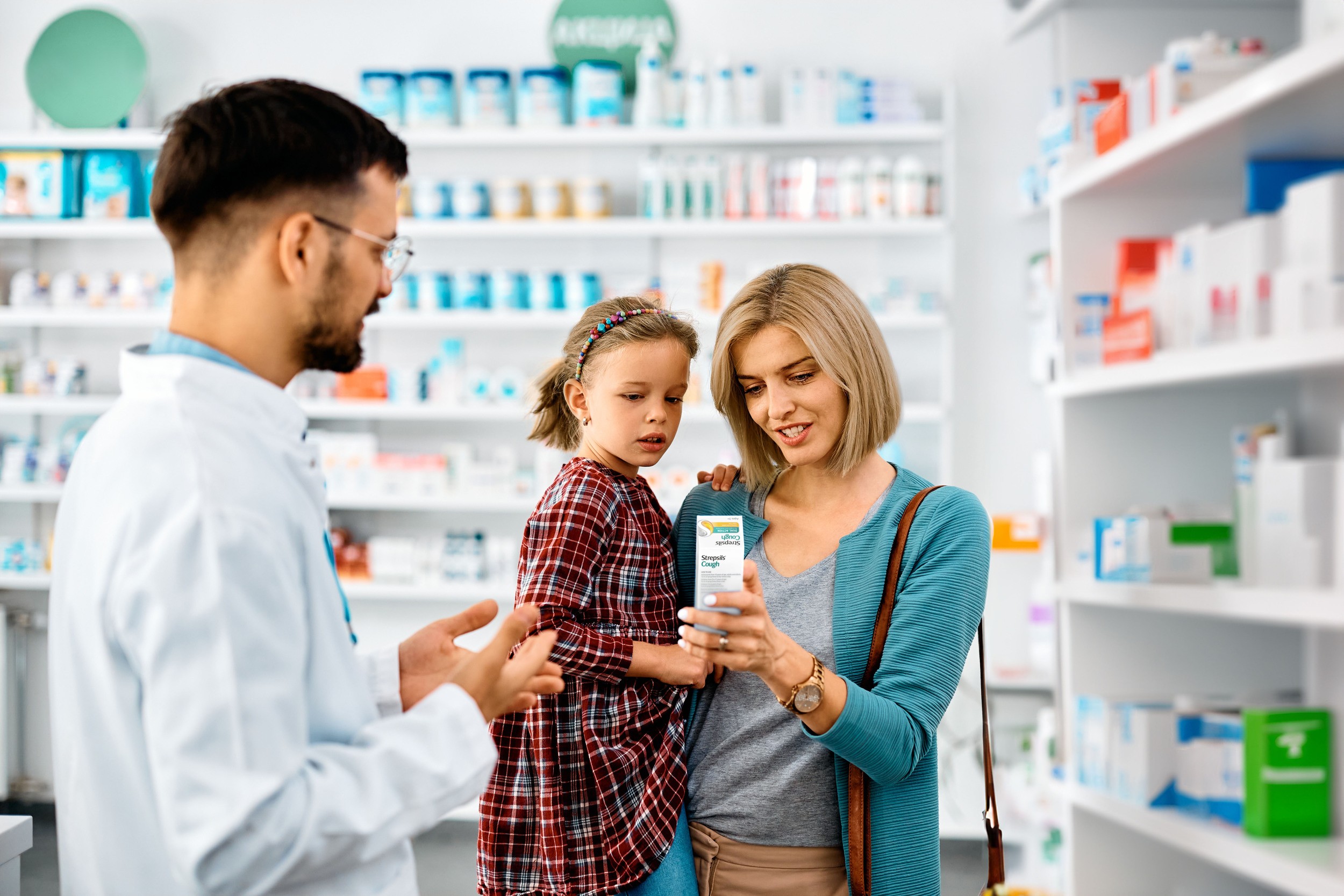Pharmacist assisting a woman and child with a medicine in a pharmacy