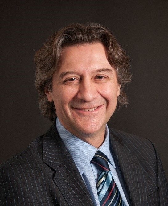 Professional headshot of a man in a dark suit and striped tie against a dark background