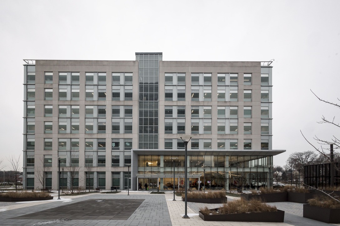 A large, modern, multi-story office building with numerous windows and a glass entrance area on a cloudy day