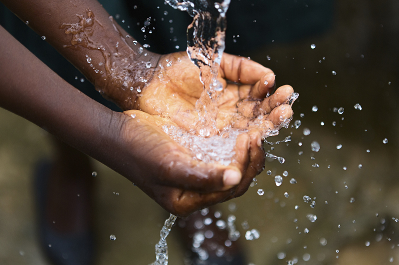 Hands catching and splashing clean water outdoors