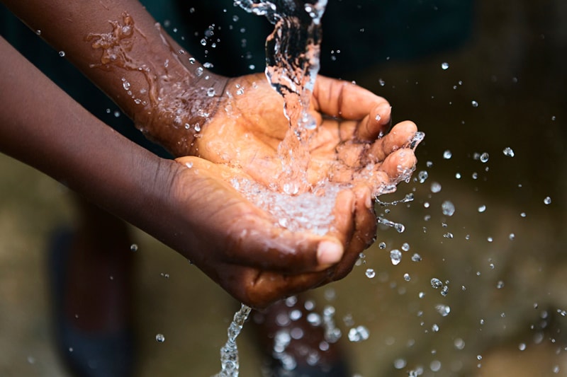 Hands catching and splashing clean water outdoors