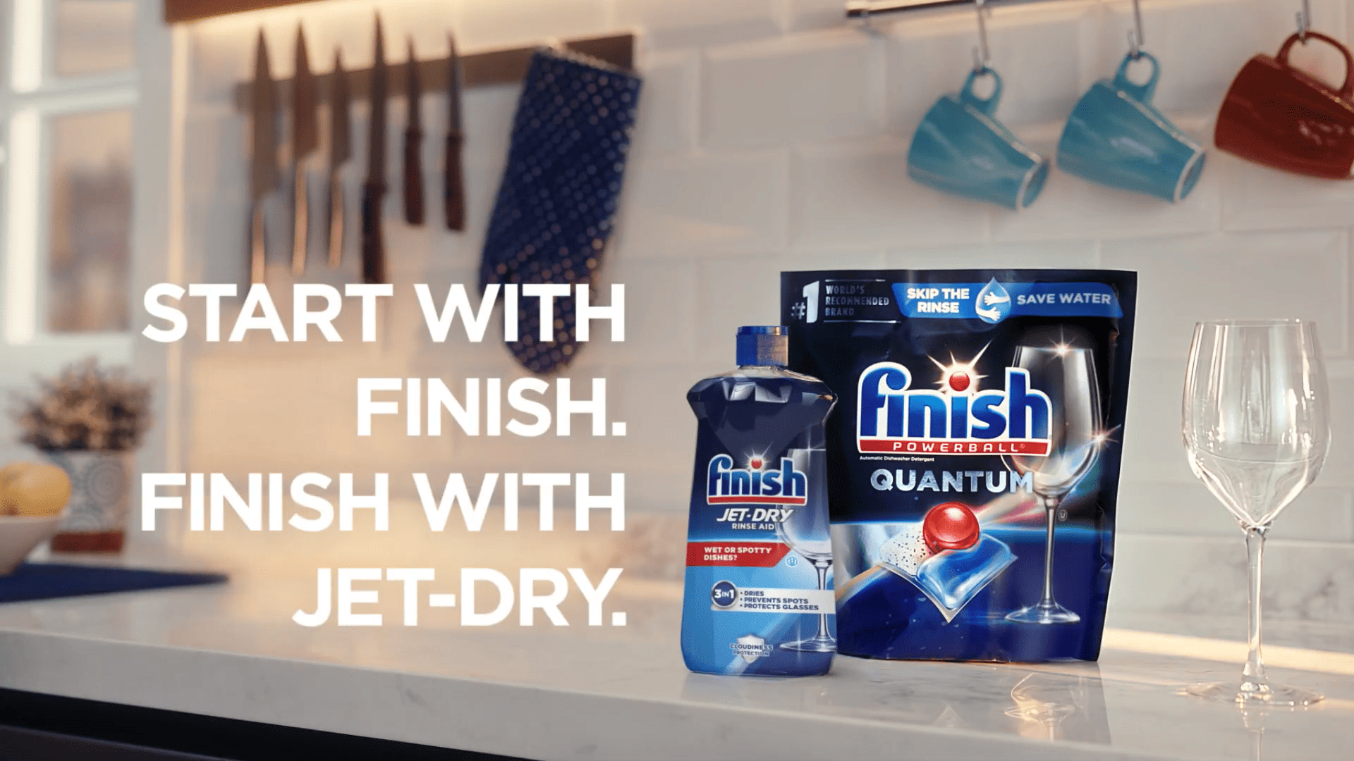 Dishwasher detergent and rinse aid displayed on a kitchen countertop beside a wine glass