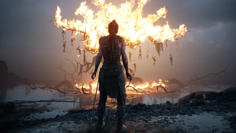 A screenshot from Hellblade: Senua's Sacrifice. Senua stands before a burning tree.