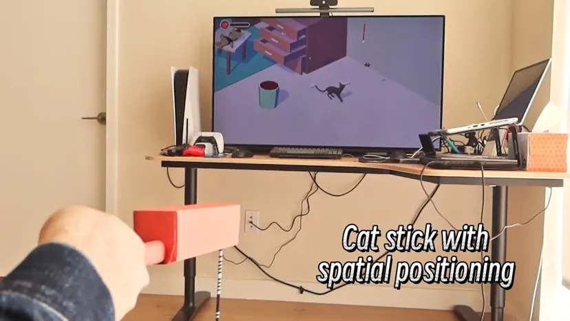 a cat character onscreen and person manipulating a stick offscreen