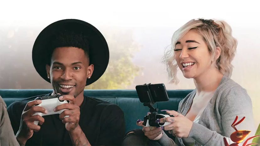 A man and a woman play on Xbox Cloud Gaming using a controller and phone, respectively.