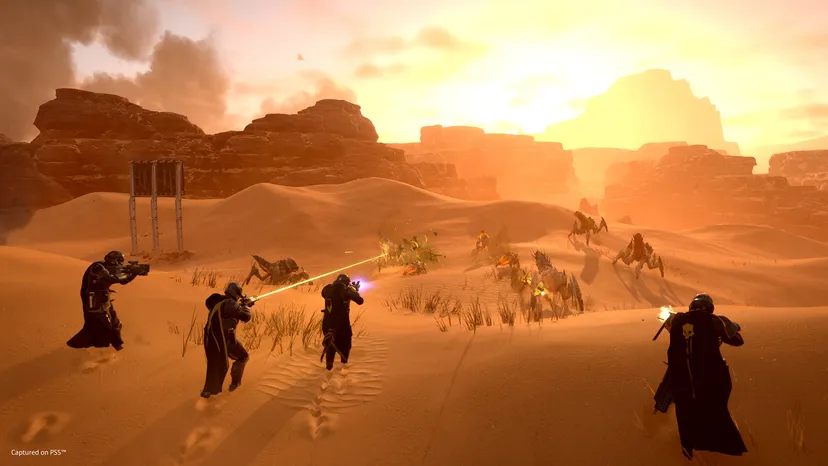A screenshot of Helldivers 2. The players fight alien bugs on a desert planet