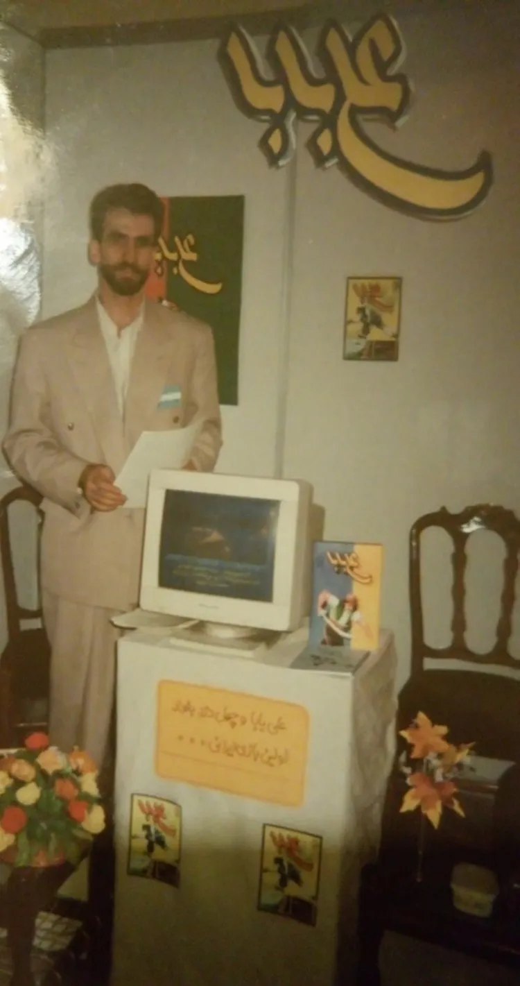 A photograph of Ramin ZafarAzizi in front of a computer playing Ali Baba.
