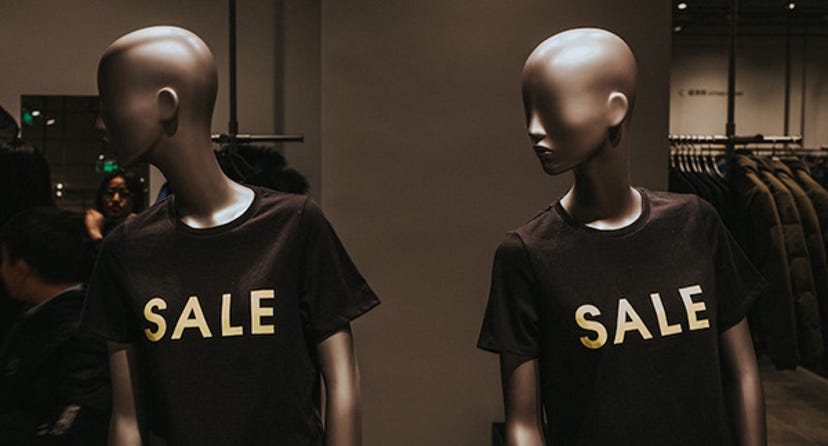 Two mannequins wear black shirts that say "sale."