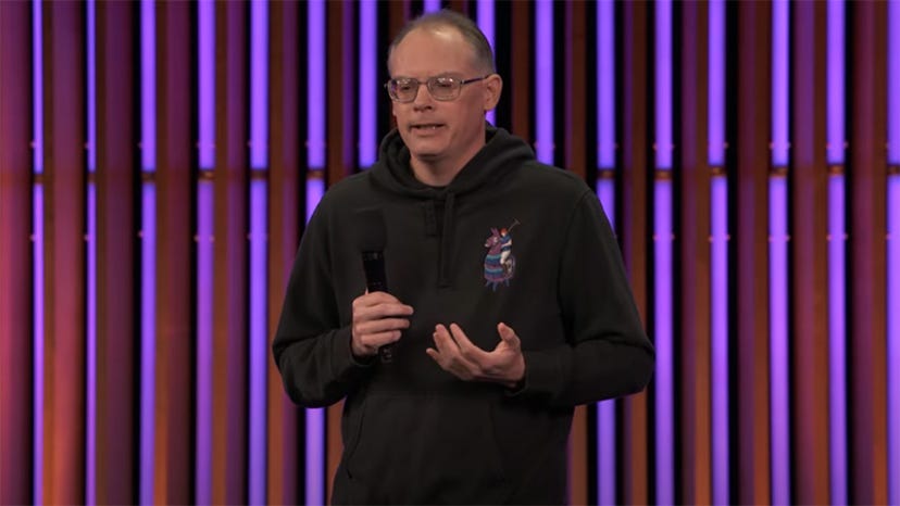 Tim Sweeney, sporting a black hoodie with a Fortnite llama on it, gives a speech at GDC 2023