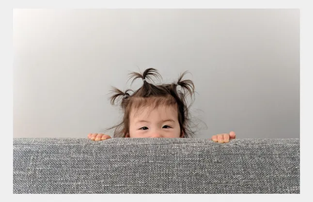 Child behind couch
