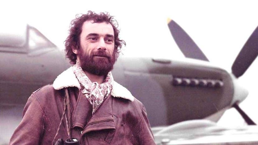 A photograph of John Gibson standing next to a plane