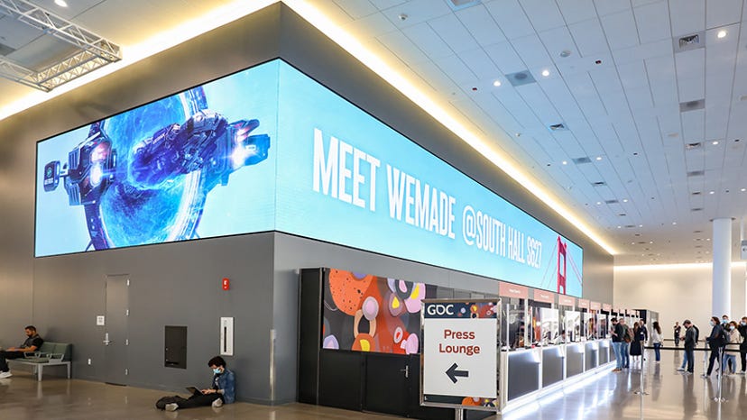 A sign for blockchain company WeMade from GDC 2022. It hangs over a registration booth.