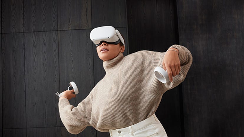 A photo of a woman using a white Meta Quest headset.
