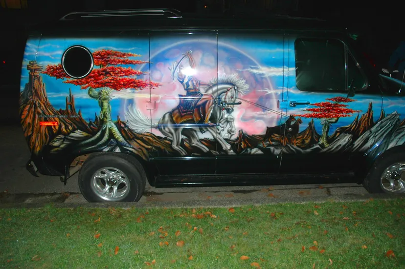 A photo of a vintage van airbrushed with a fantasy theme depicting a warrior on a horse.