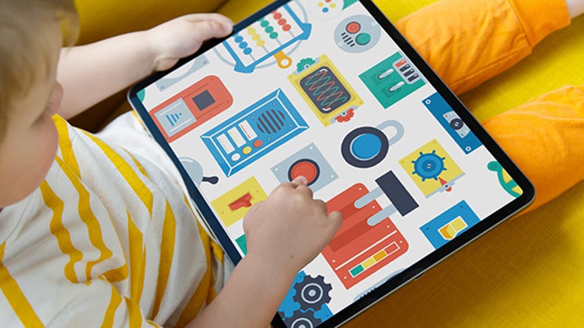 A young child plays with Pok Pok Playroom's Busy Board toy on an iPad.