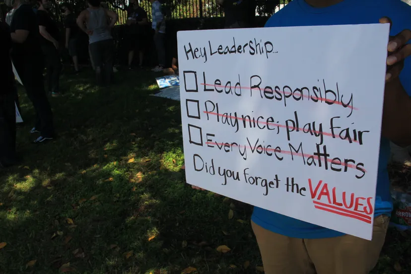 Un employé protestant de Blizzard tient une pancarte illustrant trois des valeurs de l'entreprise : 