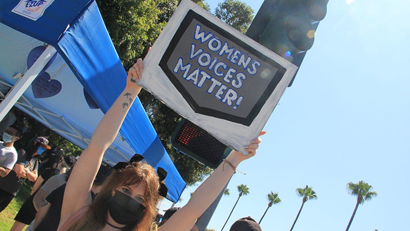 A woman holds a sign saying "Women's Voices Matter!"