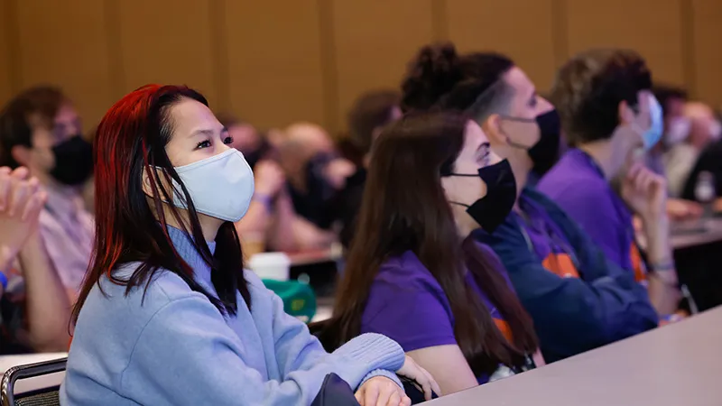 A group of masked GDC attendees watch a session.