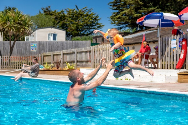 A young boy and his Dad playing in the outdoor pool at Landscove Holiday Park in Devon