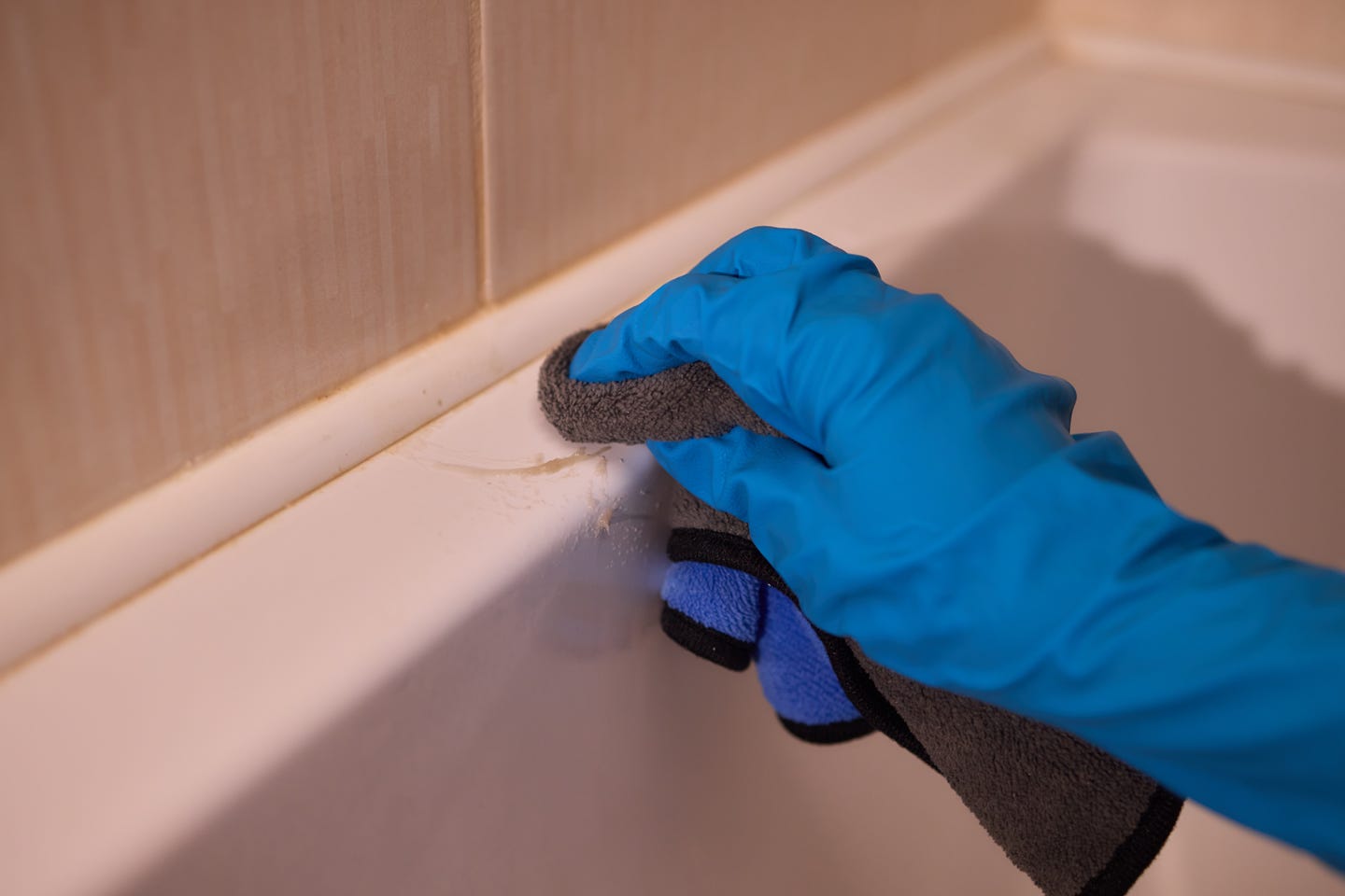 a person cleaning baseboard with a microfiber cloth